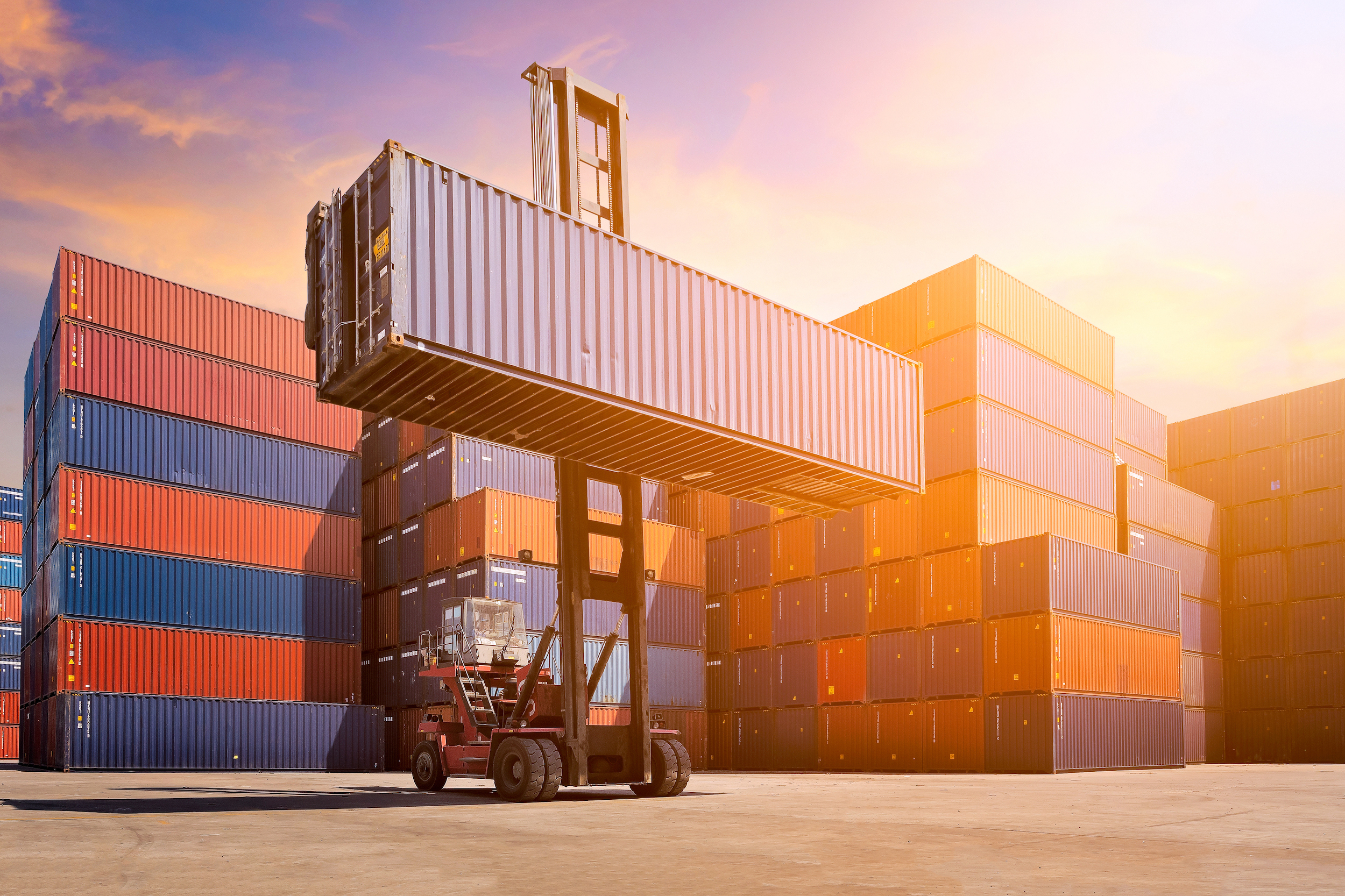 Forklift handling cargo container at shipping yard